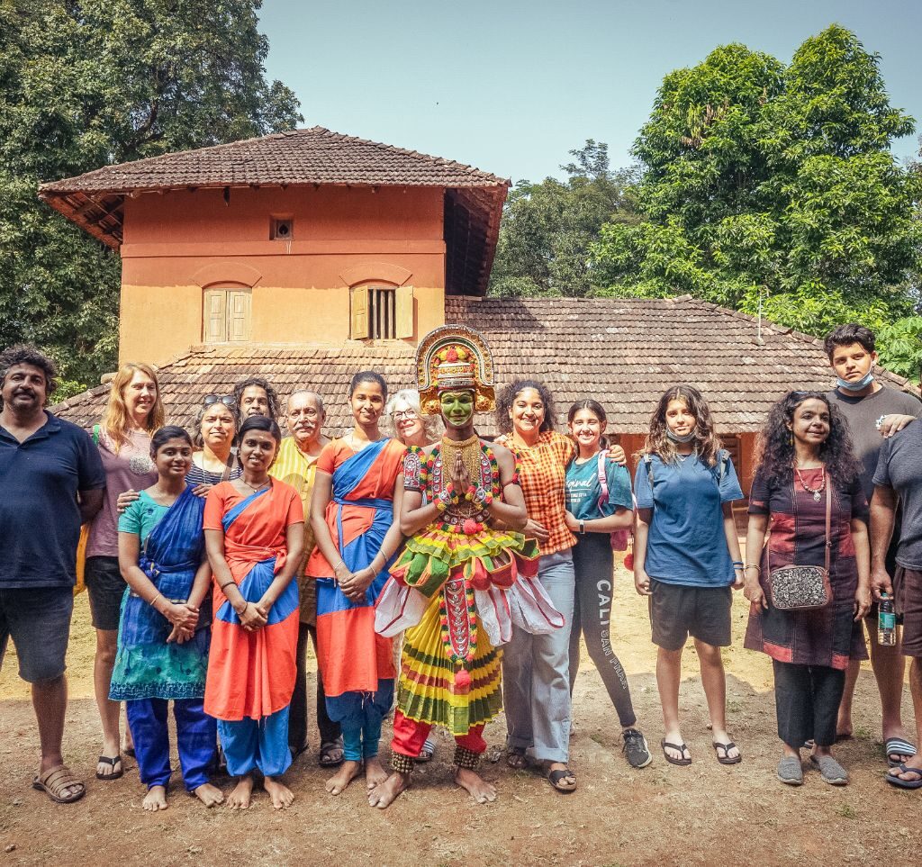 Travelers posing with the Ottanthullal performer. A tour conducted by Moksha Stories.