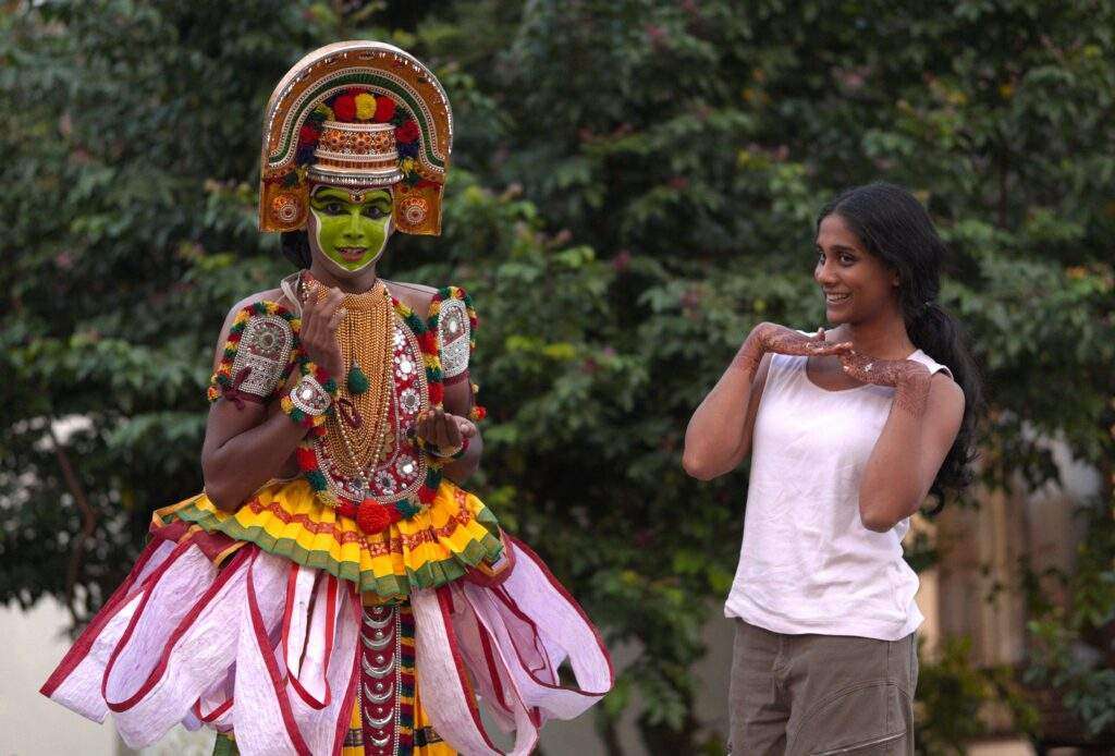 Travelers interacting with an Ottan thullal artist 
